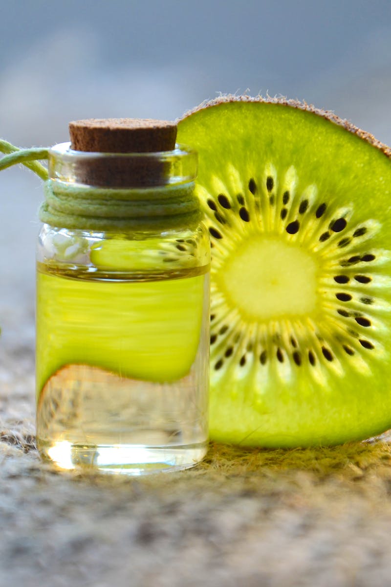 A vibrant kiwi slice next to a corked bottle with green liquid, emphasizing freshness.